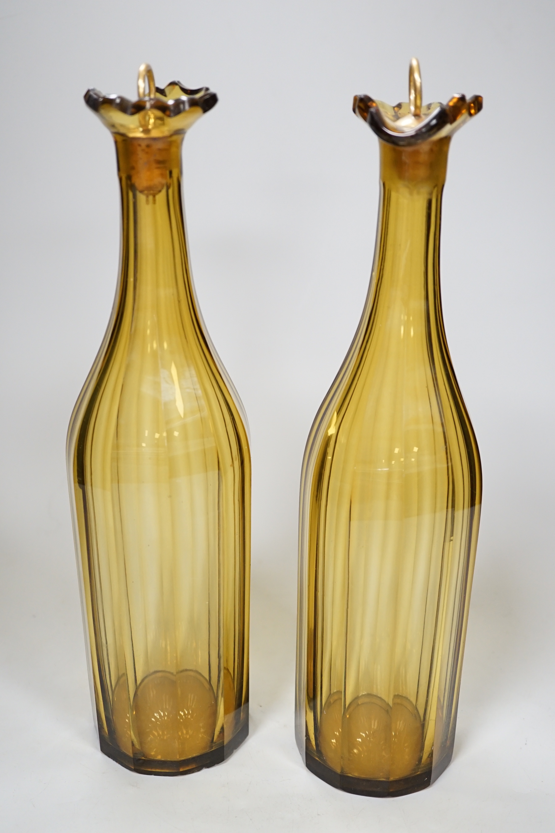 A pair of early 19th century amber panel cut glass decanters, 30cm